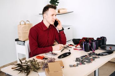 Young Eastern European man in red shirt making handmade...