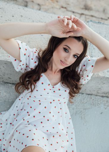 Beautiful brunette woman in summer dress sitting on...