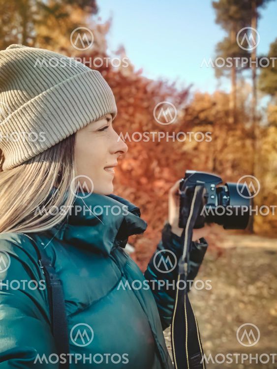Selfie portrait of young woman holding camera and taking...