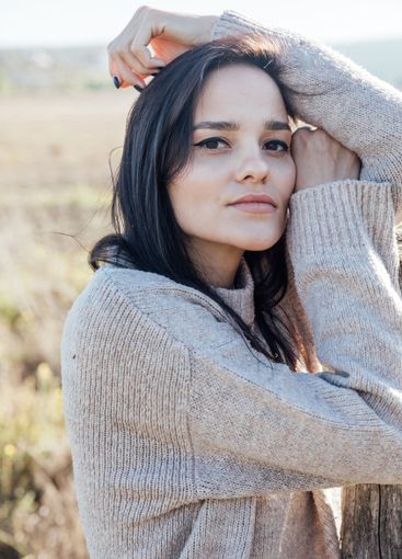 Beautiful brunette woman in sweater in rural area