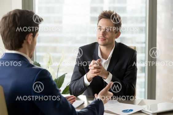 Attentive businessman listening to business partner talking duri
