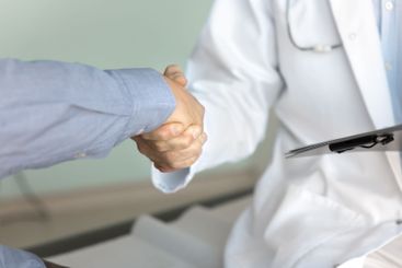 Cropped shot of male doctor and patient shaking hands