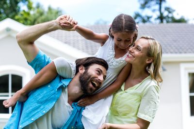 Father carrying daughter on shoulder in yard 