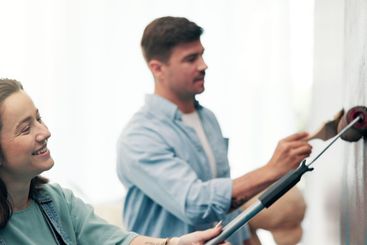 Couple, smile and painting a wall in home for diy...