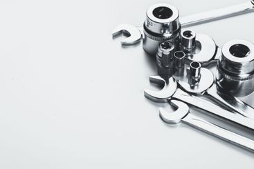 Various metallic hand tools arranged on a light surface,...