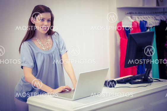 Shop worker using laptop by the till