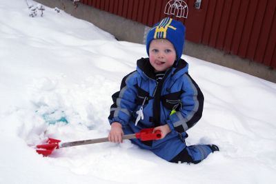 Liten pojke leker i snön