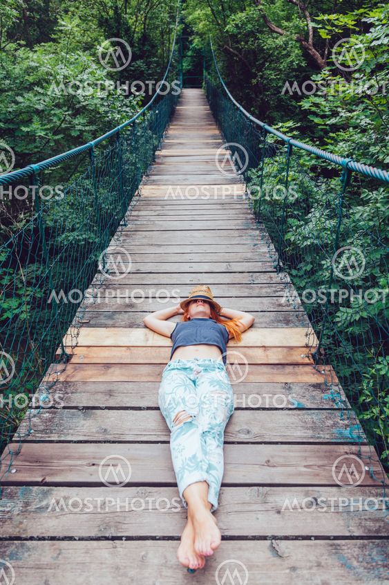 Young woman in the forest lying on the wooden bridge,...
