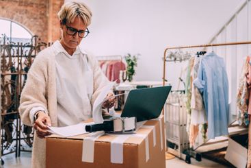 Focused female owner looking at inventory list while...