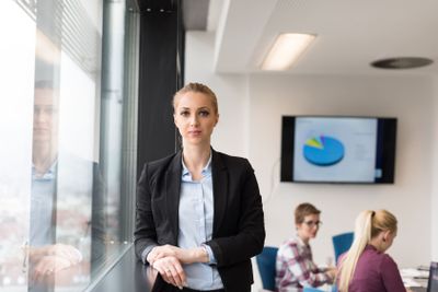 portrait of young business woman at office with team on...