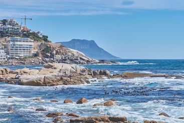 Rocks, travel and beach with waves, coastal city and...