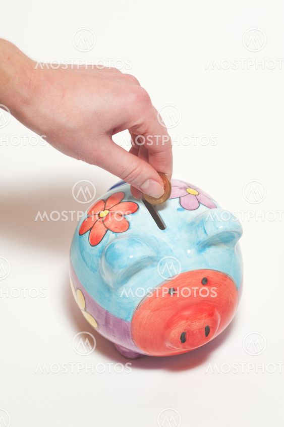 Hand is inserting a coin into piggy bank