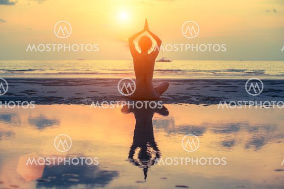 Female yoga silhouette on the beach after sunset.