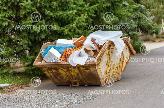 Overflowing rusty metal container for construction waste...