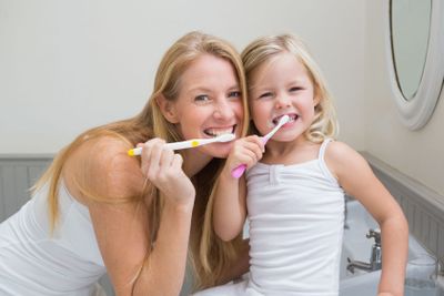 Happy mother and daughter brushing their teeth