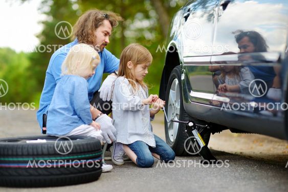 Little girl helping father to change a car wheel