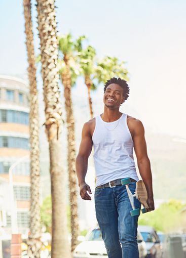 Smile, man and walking with skateboard in city for sport...