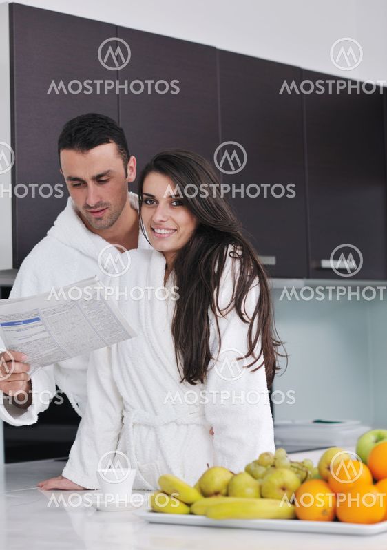 Happy couple reading the newspaper in the kitchen at breakfast
