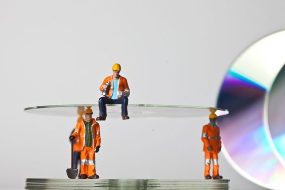 Miniature people in action with CDs