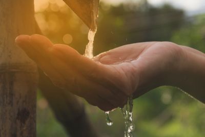 Water pouring in woman hand on nature background.