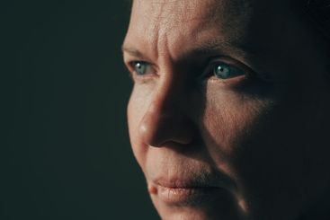 Low key image of serious mature adult brunette female,...