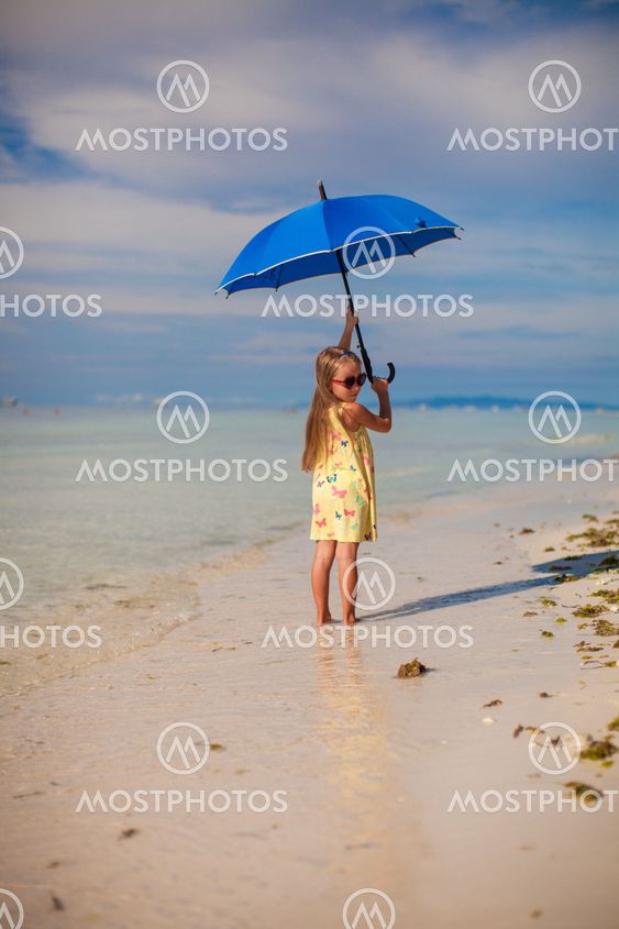 Little cute girl with umbrella have fun on exotic beach