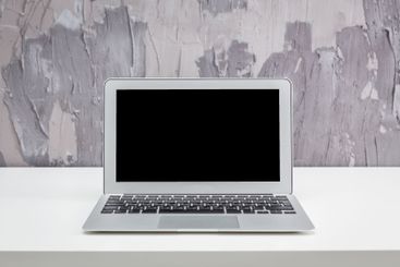 Modern laptop on a minimalist desk against a textured...