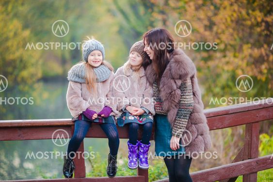 Adorable little girls with mother in autumn park...