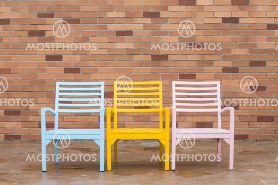 blue yellow and pink wooden chair and red brick wall