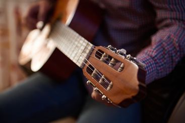 Close-up of a person playing an acoustic guitar indoors