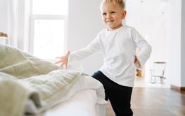 White blonde boy wearing home clothes laughing and playing