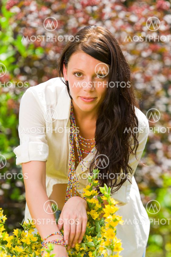 Beautiful woman sunny garden care yellow flowers