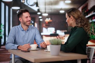 Laughing Male And Female Sitting In Cafe Drinking Coffee