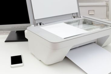 Home office setup featuring a multifunction printer, a...