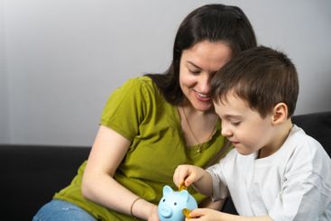 Son and mother collect money in a piggy bank. Concept of...