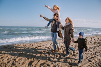 family walking on seashore in autumn