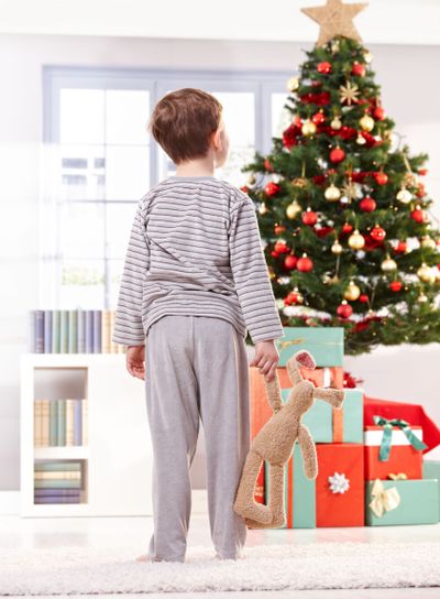 Pyjama boy with toy at christmas tree�