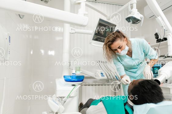 Woman dentist using x ray machine, patient lying on chair...