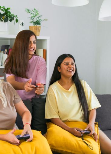 Cheerful group of friends playing video games together...