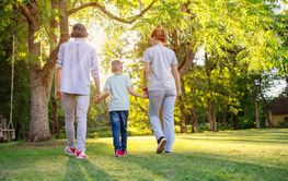 Family walking in the natural park with holding hands.