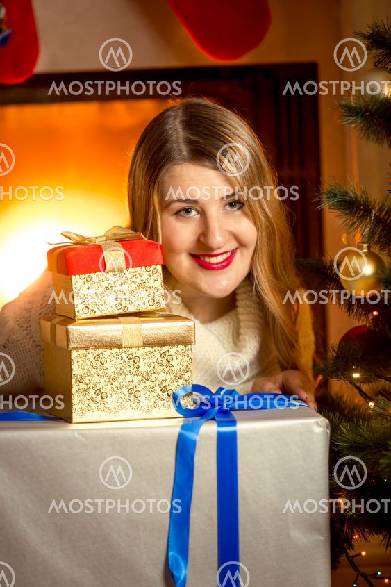 beautiful smiling woman posing with Christmas presents at...