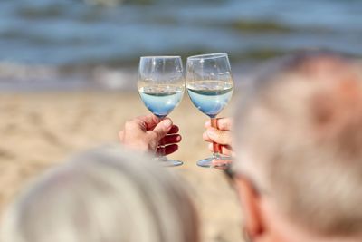 happy senior couple drinking wine on summer beach