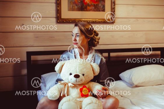 girl sitting on bed with soft toy