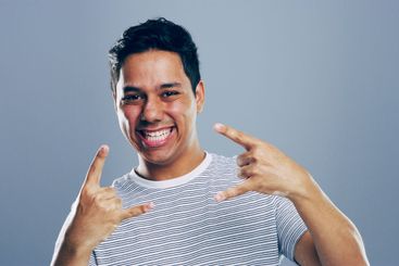 Studio, happy or portrait of Indian man with rock hand...