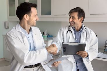 Cheerful male hospital colleagues shaking hands in...