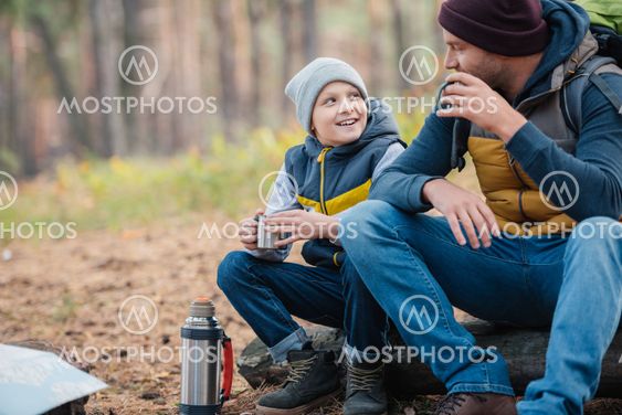 father and son drinking tea in forest