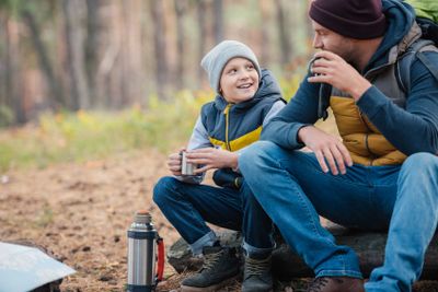 father and son drinking tea in forest
