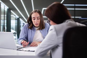 Female Tax Consultant Discussing Invoices Using Calculator