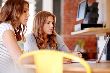 Women, twins and together at cafe with laptop, typing or...