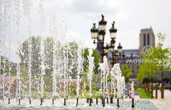 Summer in Paris. View of Notre-Dame de Paris through the fountain. Focus on the water jets
